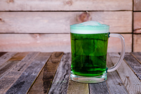 Single mug of green beer on wooden background. Tabletop, front view.の写真素材