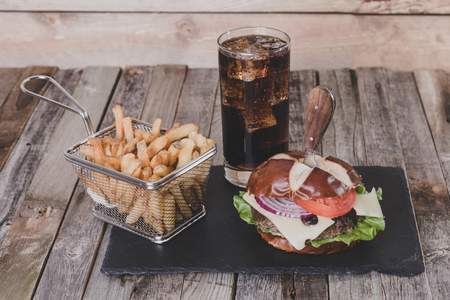 Gourmet cheeseburger with French fries and drink on wooden backgroundの写真素材
