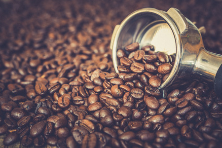 Metal espresso machine scoop on roasted coffee beans backgroundの写真素材