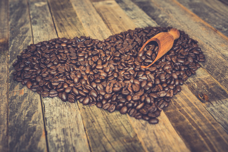Roasted coffee beans in a shape of heart on wooden backgroundの写真素材