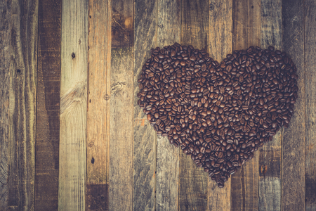 Roasted coffee beans in a shape of heart on wooden backgroundの写真素材