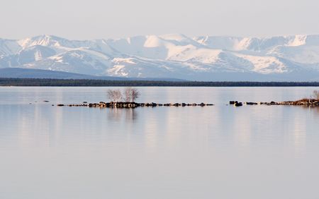 Stony island among lake on a background of mountainsの写真素材