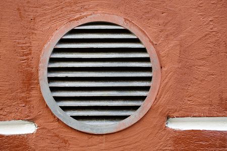 Rusty round lattice on a red wallの写真素材