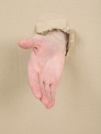 Male hand through from hole in cardboard の写真素材