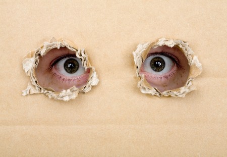 Eyes peeping through holes in a cardboardの写真素材