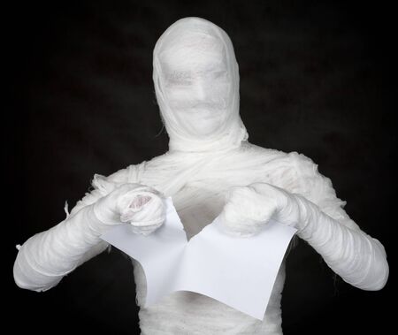 Man is costume mummy tear to piece sheet of paperの写真素材