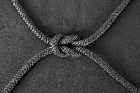 Bend knot on black cord on the black fabric backgroundの写真素材