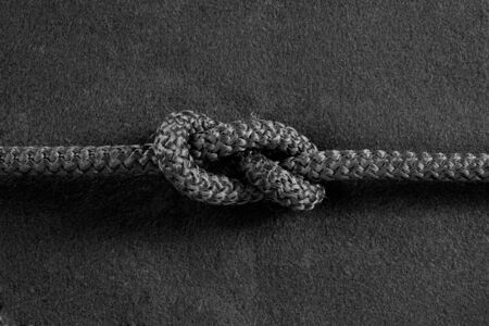 Knot on black cord on the black fabric backgroundの写真素材