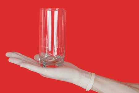 Glass on hand of water on hand on the red backgroundの写真素材