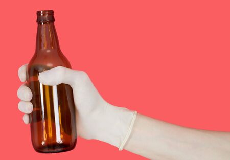 Brown bottle in hand on the red backgroundの写真素材