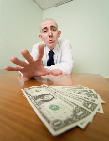 Young man reaches for a batch of money lying on a tableの写真素材