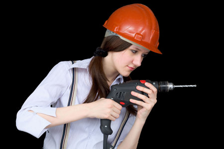 Young woman in a protective helmet with a drill in hands