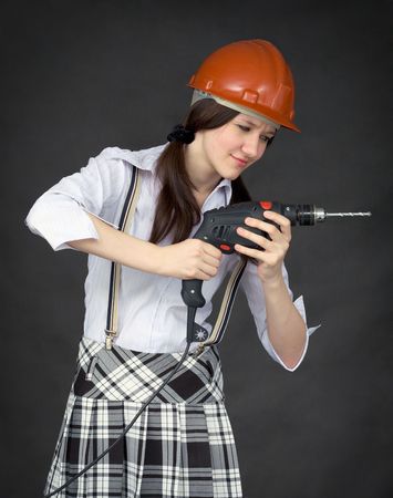 The girl in a protective helmet learns to use a drillの写真素材