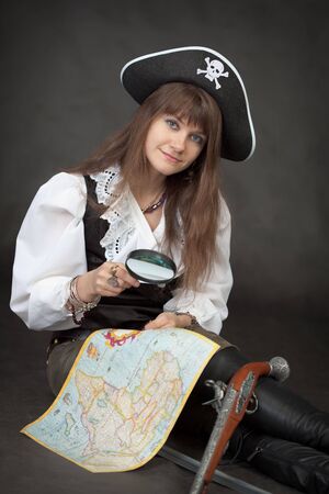Pirate girl with sea map and pistol sit on a black backgroundの写真素材