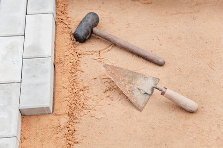 Tools of the mason on a sand surface - trowel and hammerの写真素材