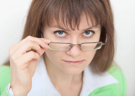 The strict young woman looks at us over eyeglassesの写真素材