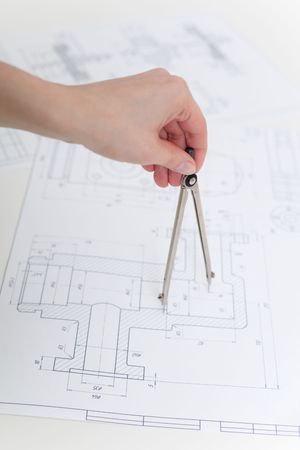 The hand holds metal compasses against drawingsの写真素材