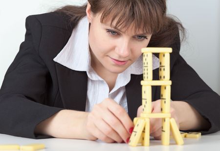 The young girl in black concentrated builds on a table a tower of dominoesの写真素材