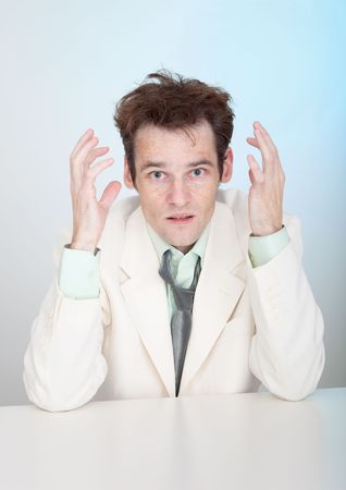 The young sorrowful man in a white suit sits at a tableの写真素材