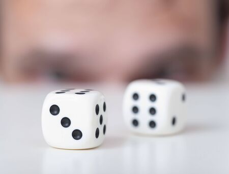 Two white playing cubes against a man faceの写真素材
