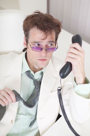 The businessman emotionally speaks on the phone at officeの写真素材