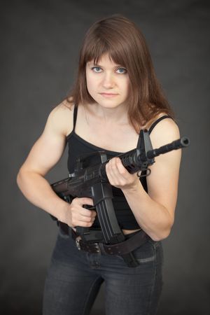 The woman - the fighter of special troops with a rifle in hands against a dark backgroundの写真素材