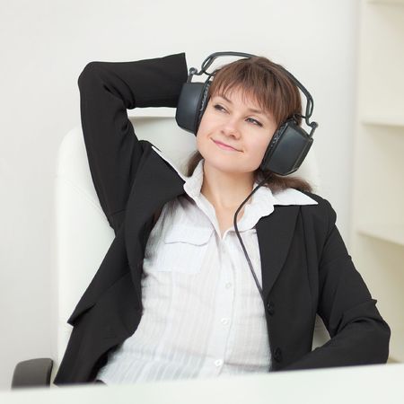 The young girl with the big professional ear-phones on a head sits in an armchairの写真素材