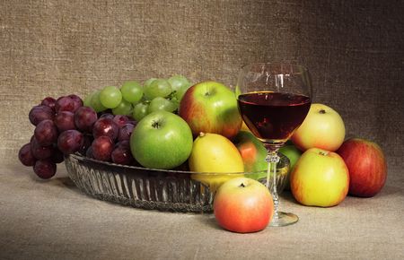 Classical still-life with fruit and a glass of red wine against a canvasの写真素材