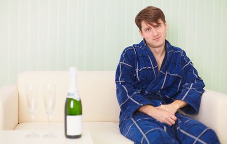 The guy in expectation of the woman with sparkling wine on a sofaの写真素材