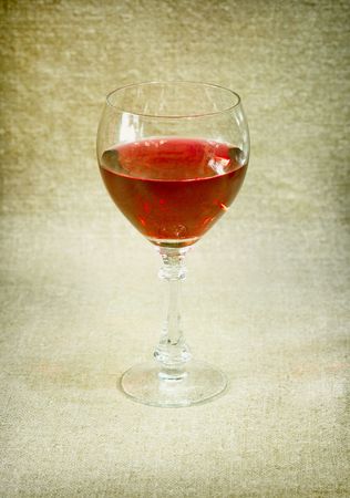 One glass with red wine against a brown draperyの写真素材