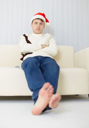 The person in a Christmas cap sits on a sofa and watches TVの写真素材