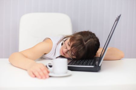 The young woman comically sleeps on the laptop at officeの写真素材