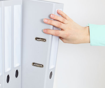 The female hand gets from a shelf a folder with accounting documents