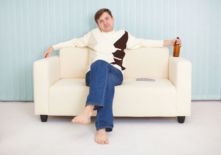 The young guy has a rest on a sofa with beer and the TVの写真素材