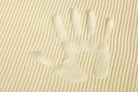 Trace from a palm on a surface of yellow sand