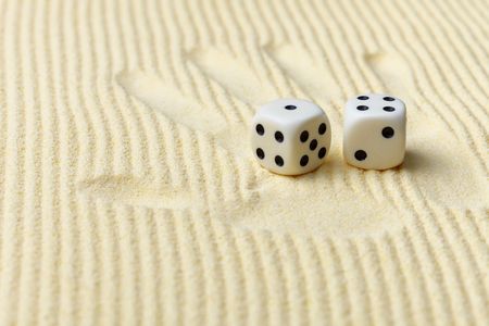 Dices on a sand surface and a palm print - an abstract art composition in yellow tonesの写真素材