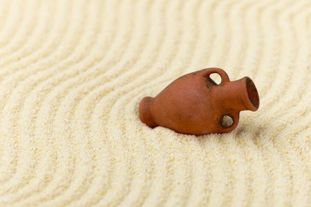 The ancient clay amphora lies on a surface of yellow sandの写真素材