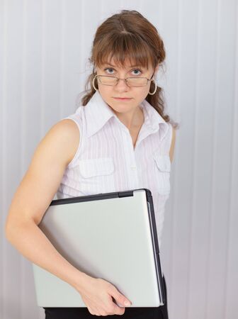 The serious girl holds the closed laptop in a handの写真素材