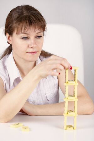 Young woman builds a precarious tower of dominoesの写真素材