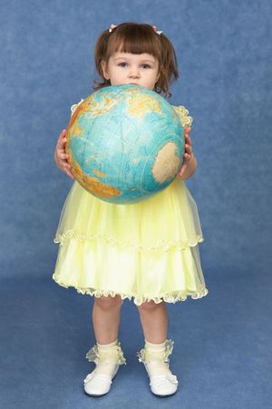 Little girl holding a large globe on a blue backgroundの写真素材