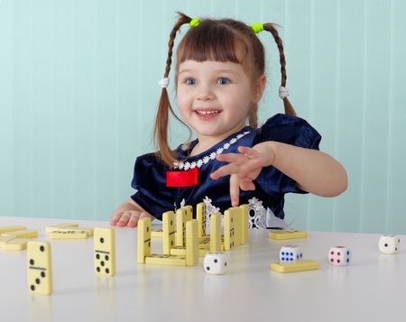 Cheerful child playing with small toys, sitting at the tableの写真素材
