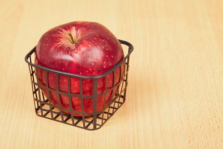Red apple in a small basket on a wooden backgroundの写真素材