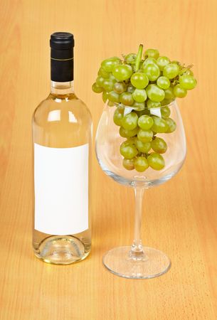 A bottle of wine, a large glass and grapes on wooden backgroundの写真素材
