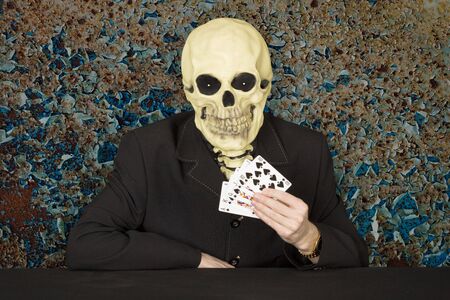 Horrible cardsharper in a mask - the skull sitting at the tableの写真素材