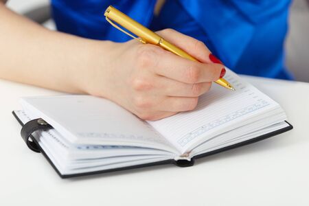 She takes notes in a notebook with penの写真素材