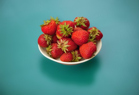 Strawberries in bowl on a blue backgroundの写真素材
