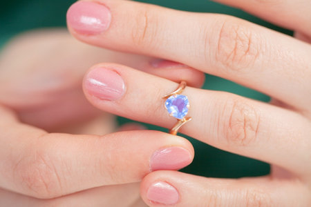 The Golden Ring with a dark blue jewel try on a finger
