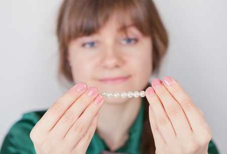 The young girl admires a beads from pearls close upの写真素材