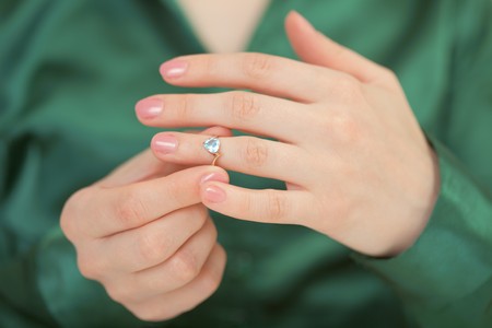 Gold ring decorated with a blue brilliant on a female handの写真素材