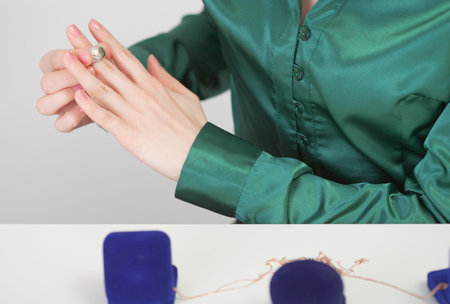 The woman tries on jewels sitting at a table